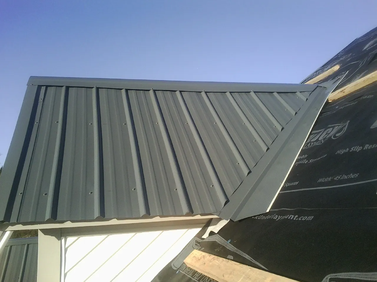 Gray metal roof panels going on over a garage gable in Guthrie