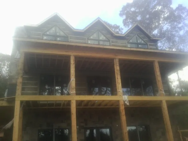 Dormers and porch framing on a large log home under construction — Roof Coating work by our crew in Guthrie