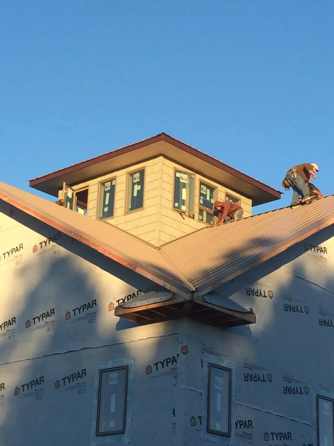 Roofers working around a rooftop cupola on a new metal roof at sunset — Roof Waterproofing in Guthrie by Roofing Brothers